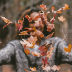 Woman relaxing outdoors in soft autumn light, reflecting steady mood and energy through the seasonal hormone shift